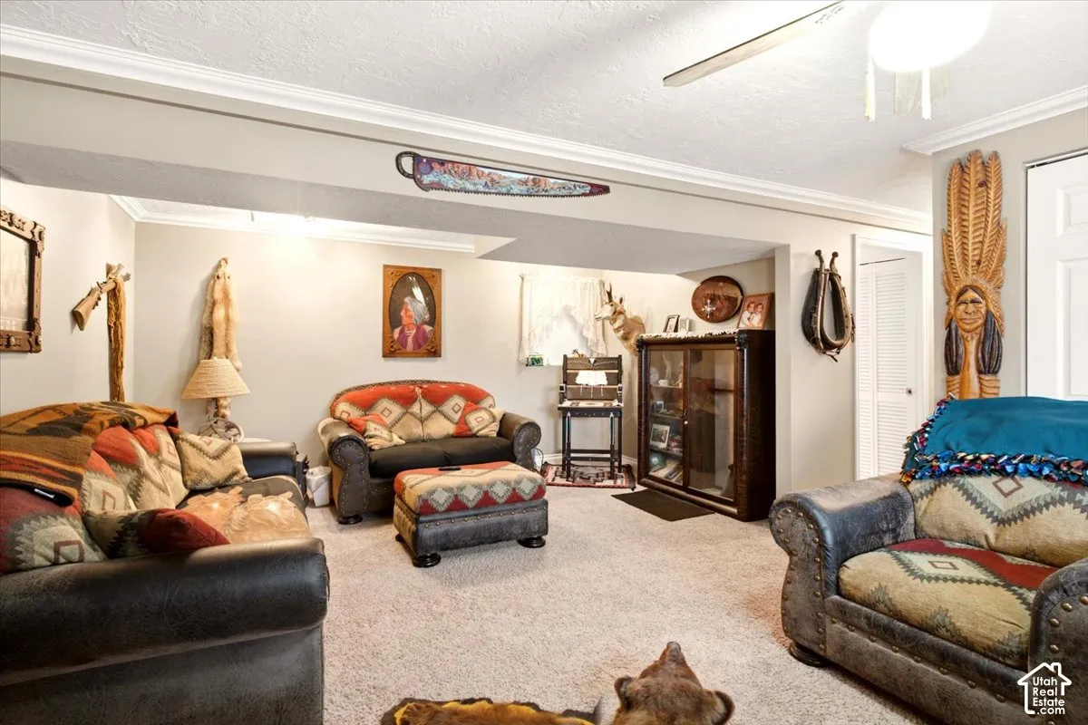 Featuring neutral wall tones, crown molding, wall-to-wall carpeting, a ceiling fan, and louvered closet doors