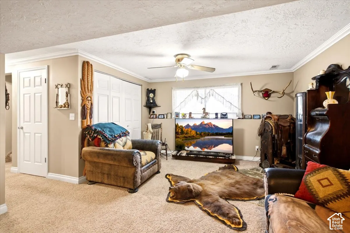 Featuring neutral-toned walls, crown molding, wall-to-wall carpeting, a multi-panel door, and a ceiling-mounted light fixture with an integrated fan