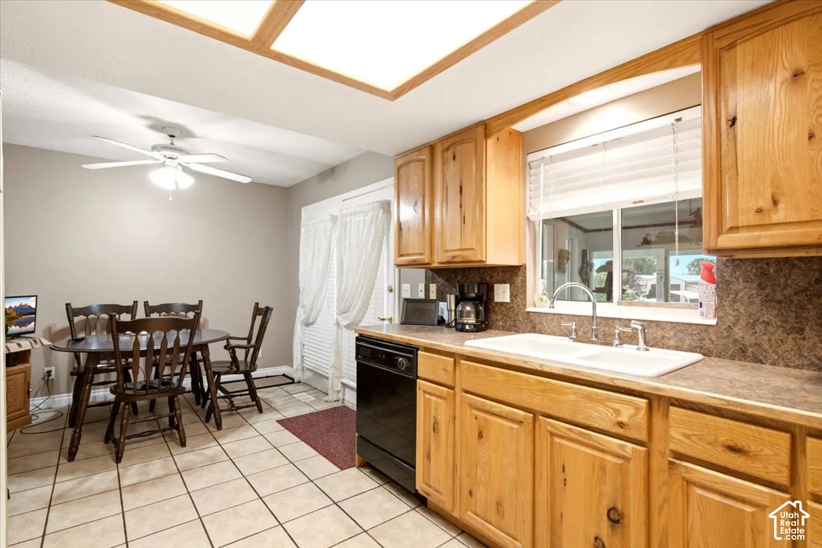 Kitchen featuring natural wood cabinetry, dual-basin white sink, laminate countertops, tile flooring, and integrated ceiling lighting