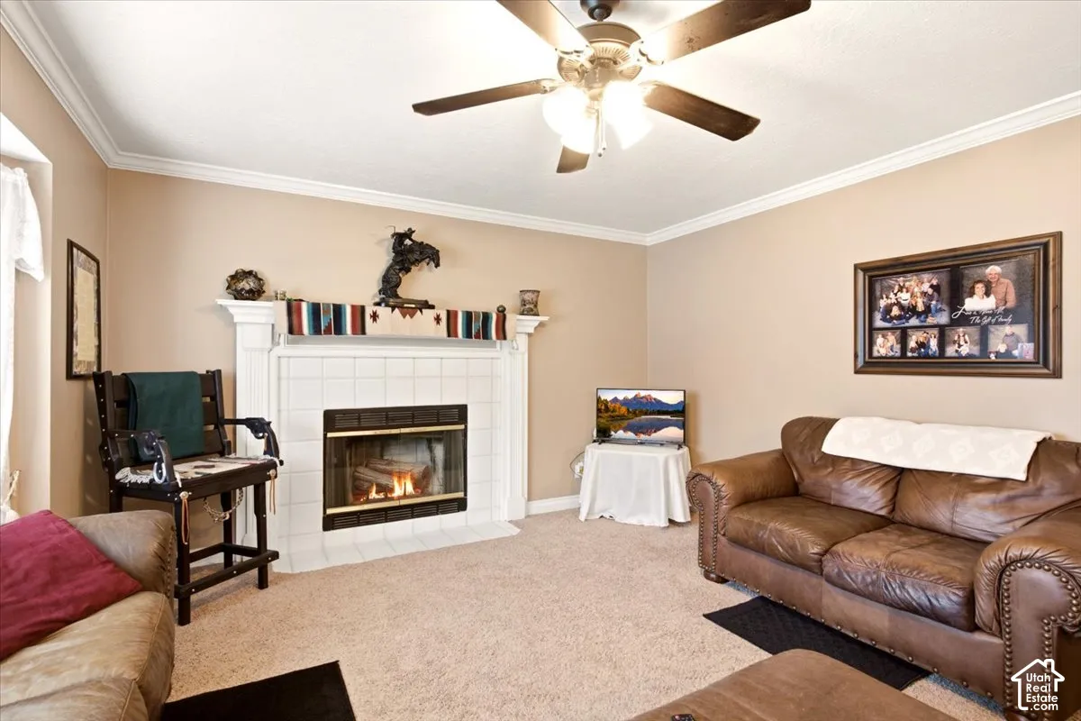 Fireplace featuring a white mantel and surround with a tile hearth, crown molding, and a ceiling fan with integrated lighting