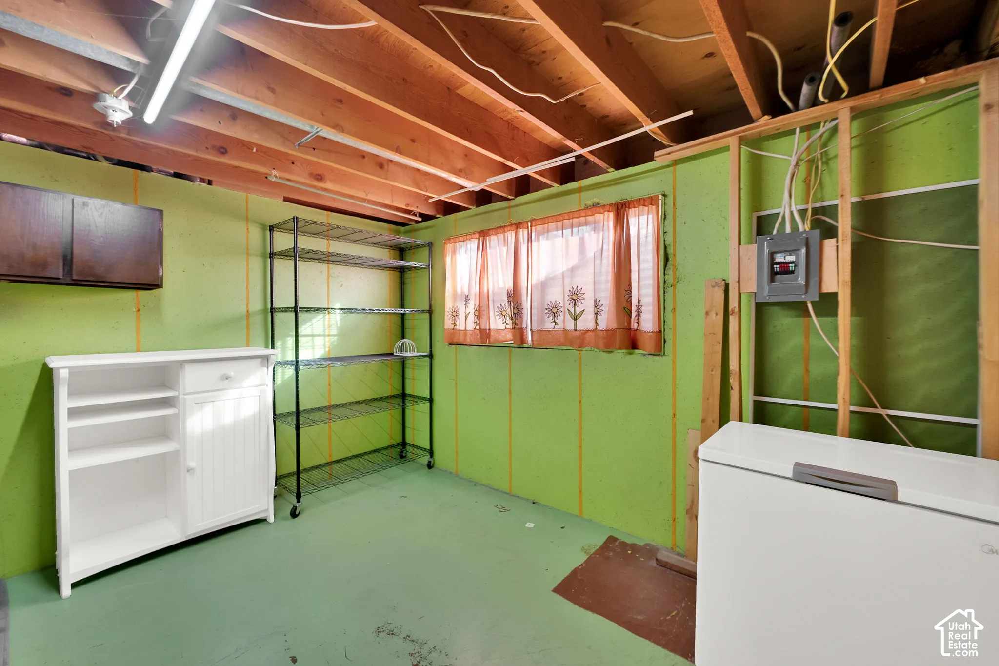 Utility room featuring exposed ceiling joists, finished floor, and wall-mounted electrical panel
