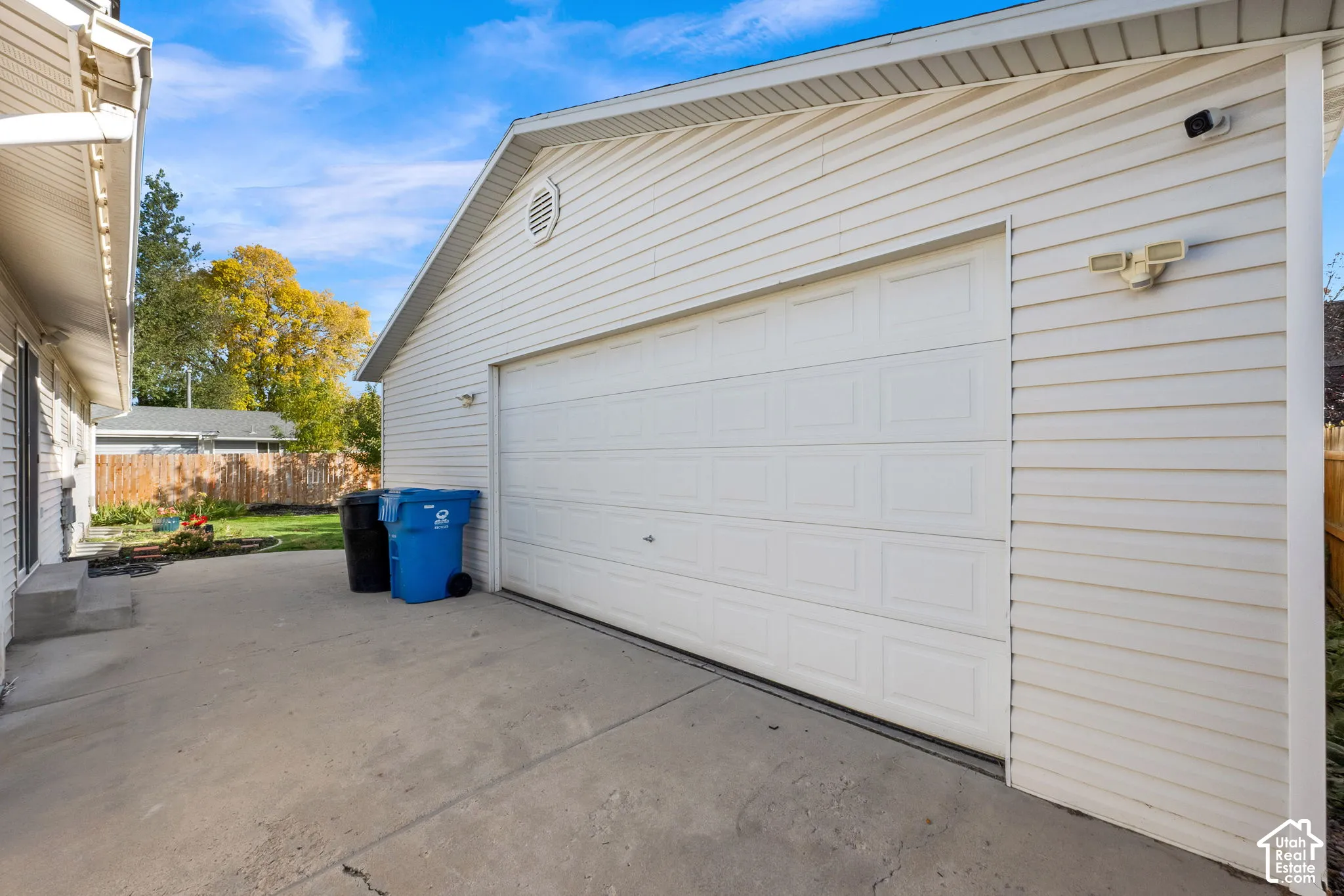 Detached garage featuring white horizontal siding, a paneled overhead door, and concrete driveway space