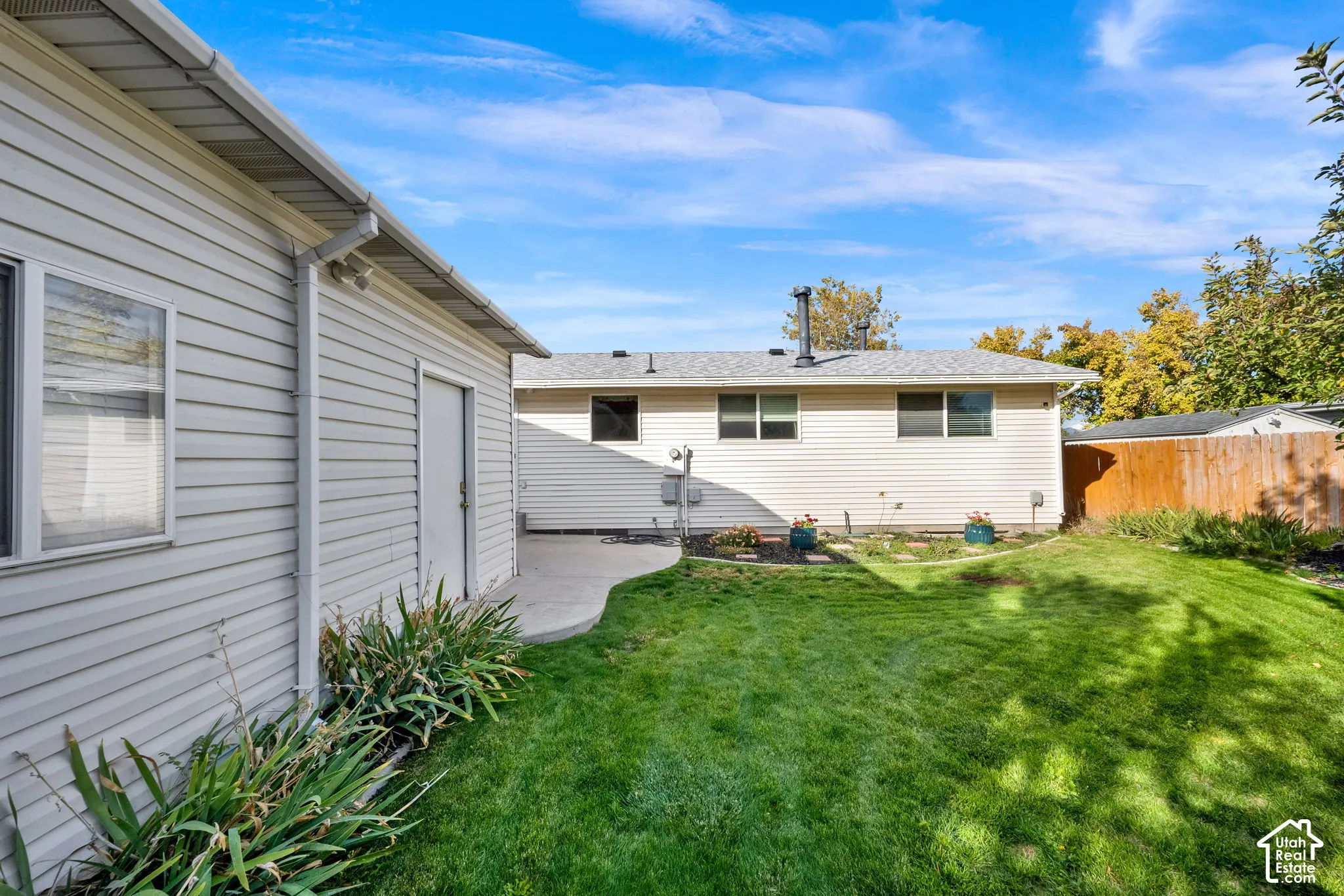 Exterior siding, concrete patio, grass lawn, and wood-style privacy fencing