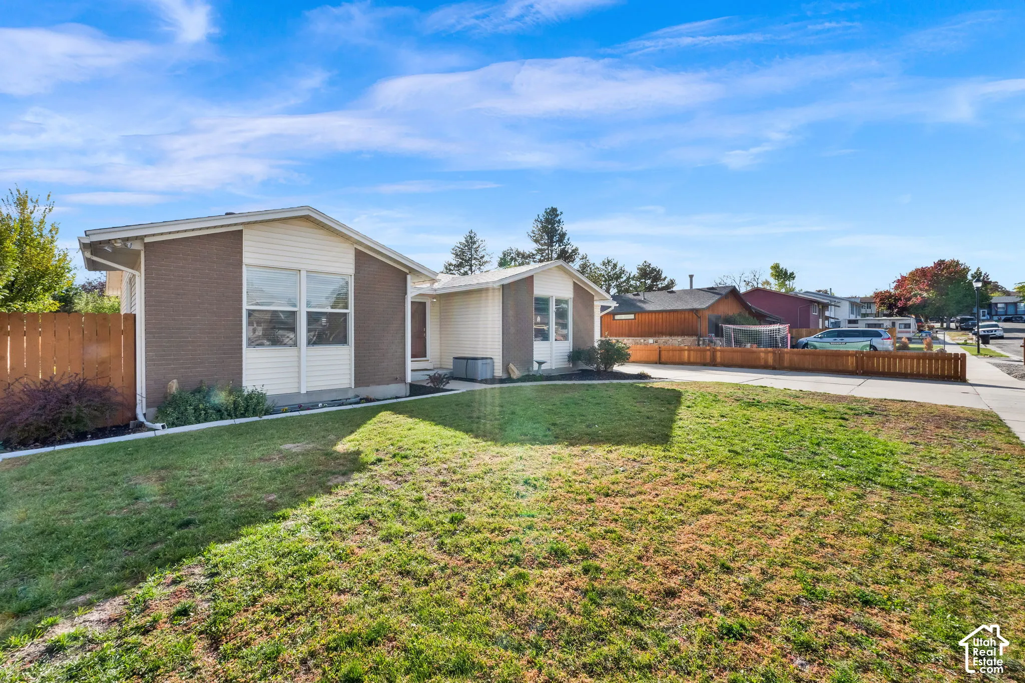 Single-story residence featuring a brick and horizontal siding exterior, expansive front lawn, and perimeter wood fencing