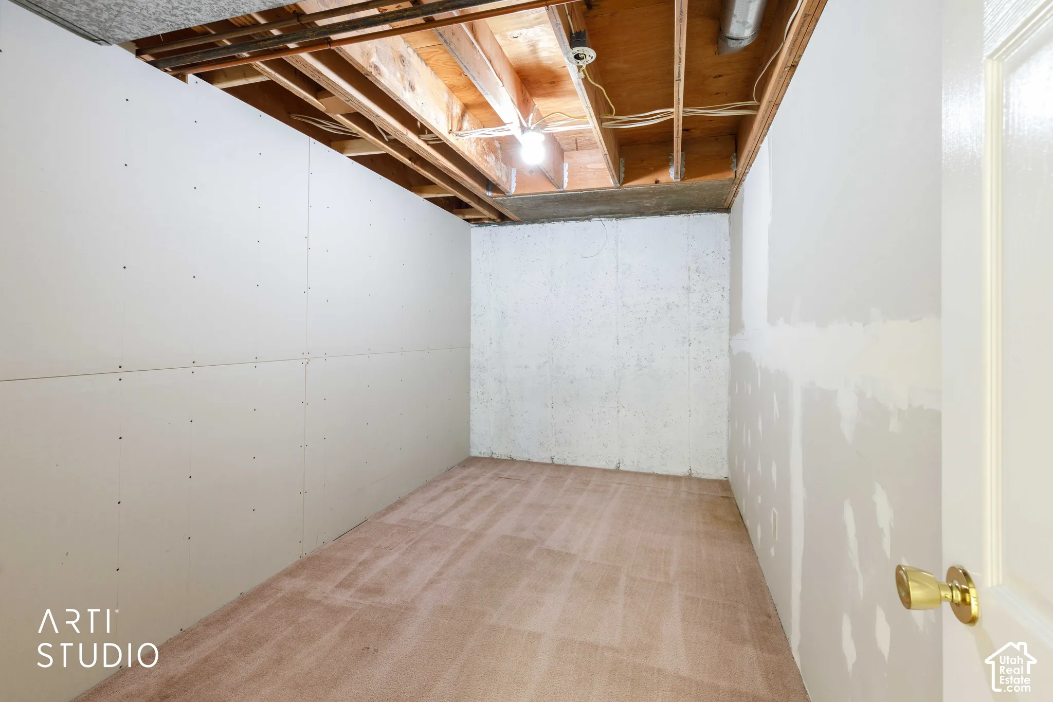 Unfinished space featuring gypsum board wall panels, exposed wood-frame ceiling joists, and concrete foundation walls