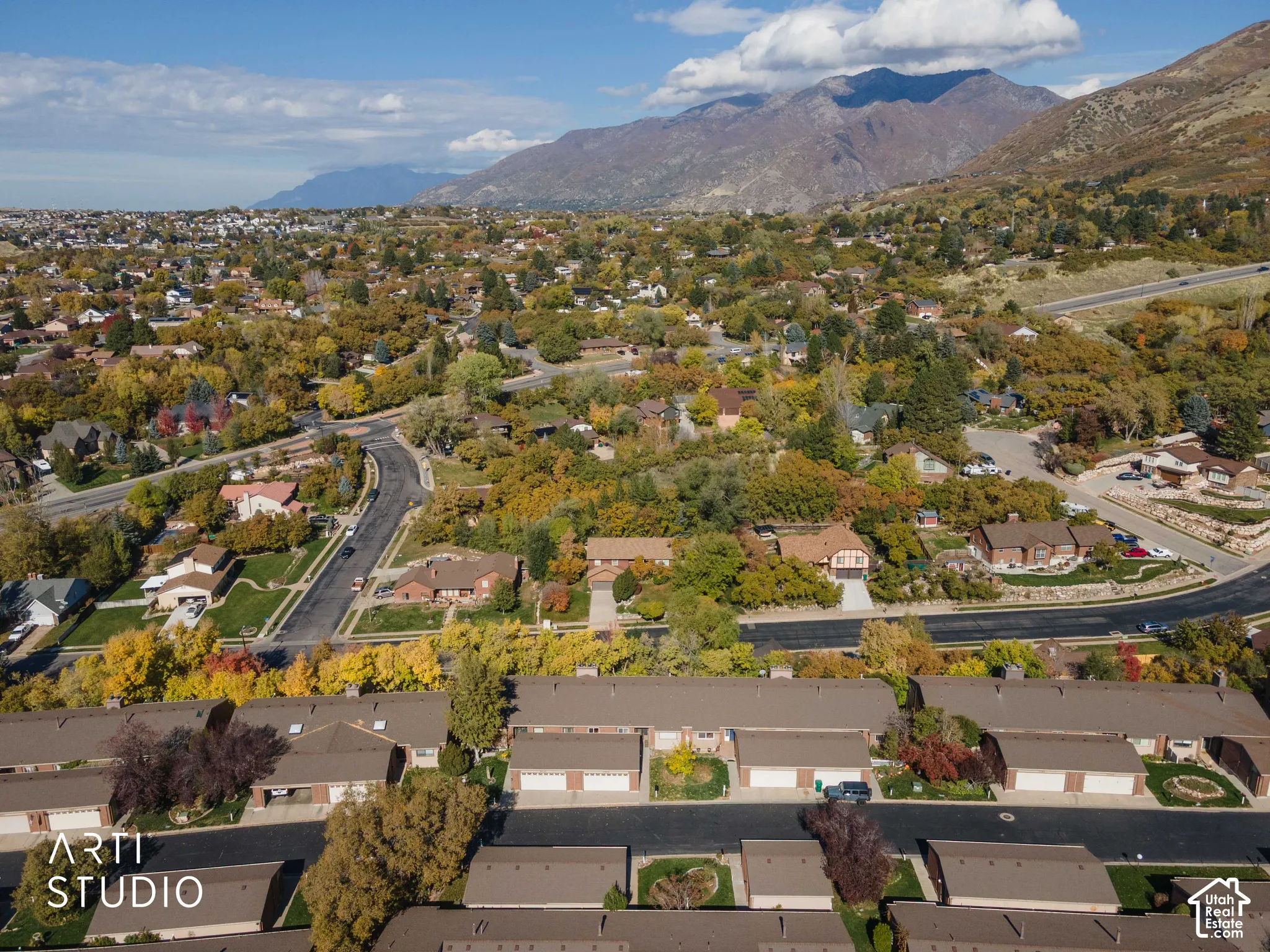 Aerial perspective featuring multi-unit dwellings with attached garages, shingled roofing, and a backdrop of mountain ranges