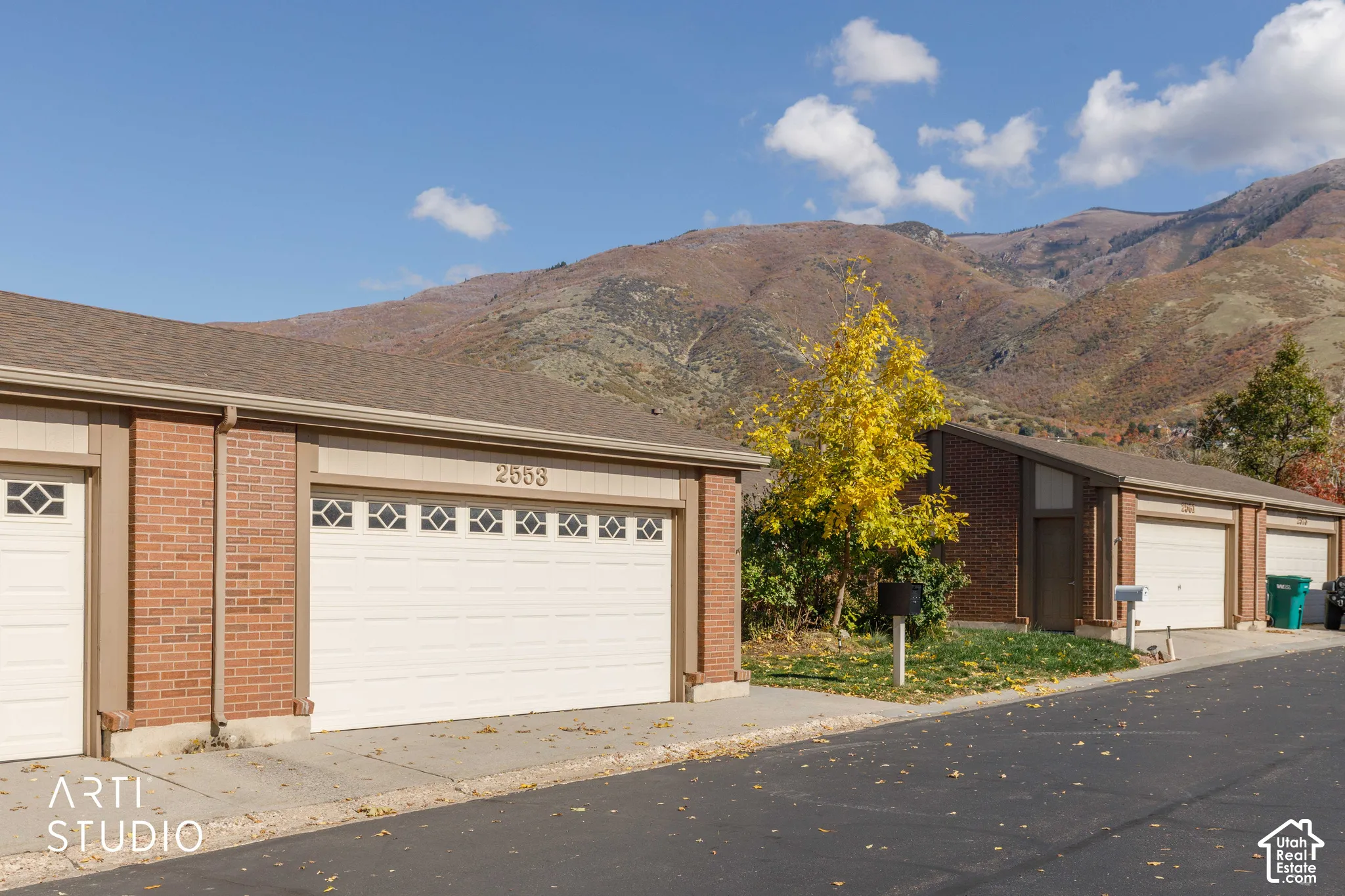 Exterior featuring brick siding, multi-car garage with paneled doors, and mountain backdrop