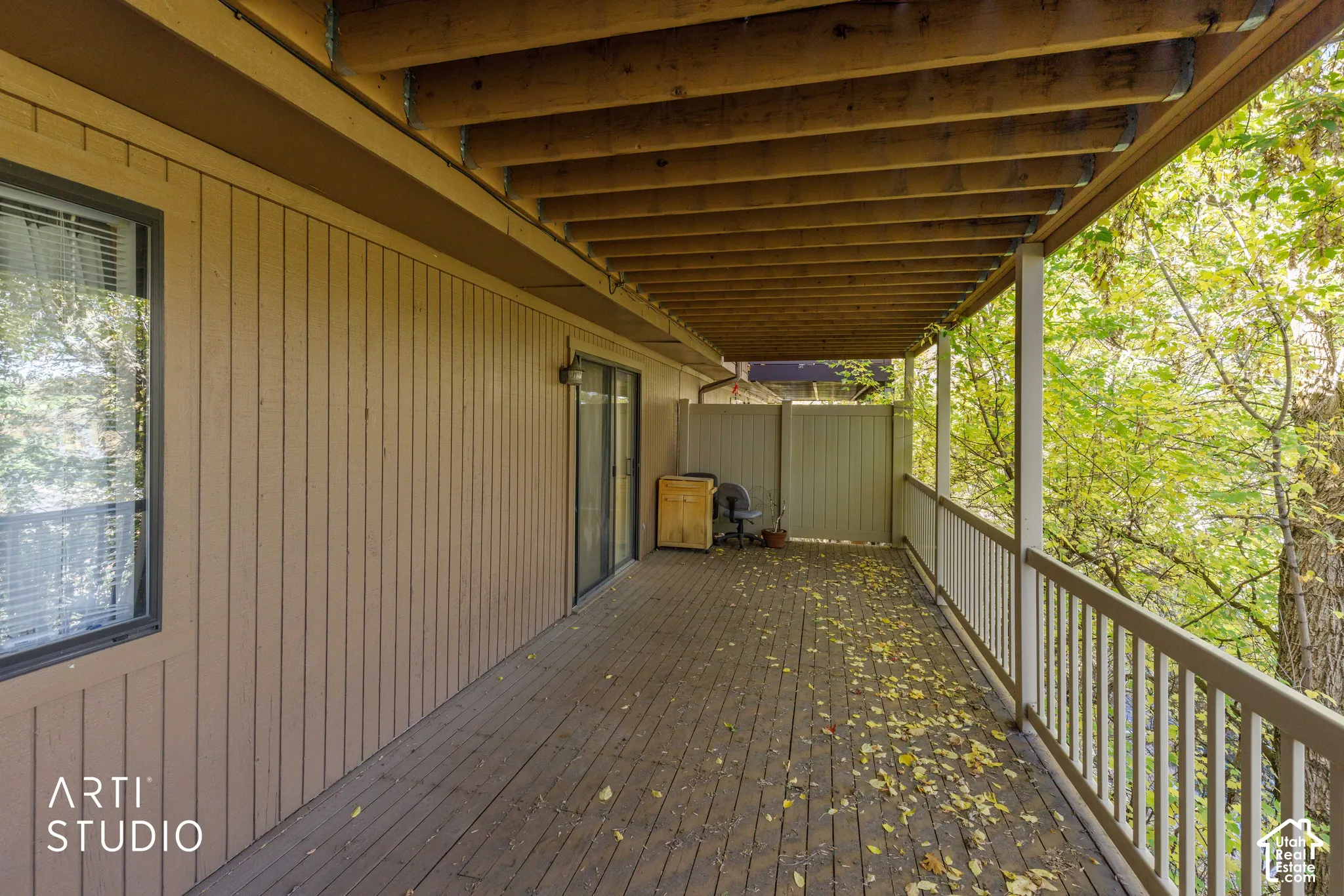 Covered wood deck featuring vertical wood siding, a wooden support beam ceiling, and a full-length painted railing