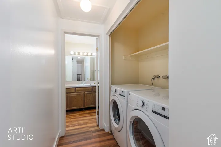 Laundry alcove featuring built-in shelving, wood-finish flooring, and a vanity with cabinetry and a fixed mirror