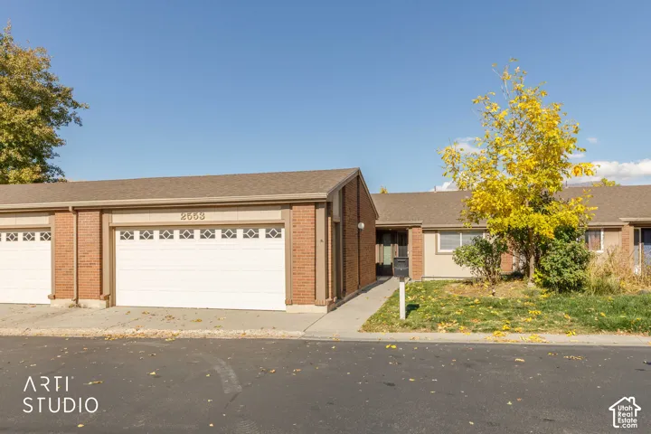 Exterior facade featuring red brick masonry, neutral-toned vertical siding, attached dual-car garages with decorative windows, and concrete driveway