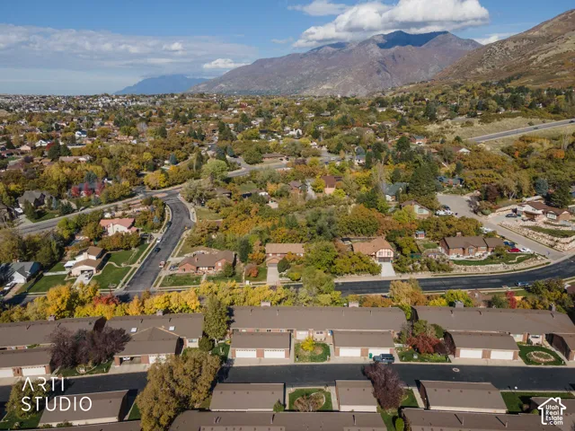 Aerial perspective featuring multi-unit dwellings with attached garages, shingled roofing, and a backdrop of mountain ranges