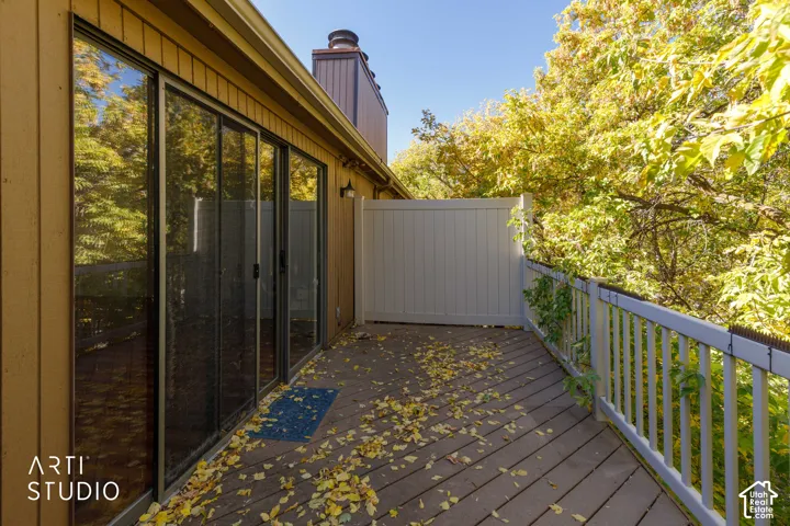 Wood-plank decking featuring a white vinyl privacy screen and vertical balustrade railing, accessible via sliding glass doors