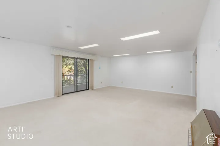 Expansive room featuring wall-to-wall carpeting, recessed and linear fluorescent lighting, and sliding glass doors with exterior access