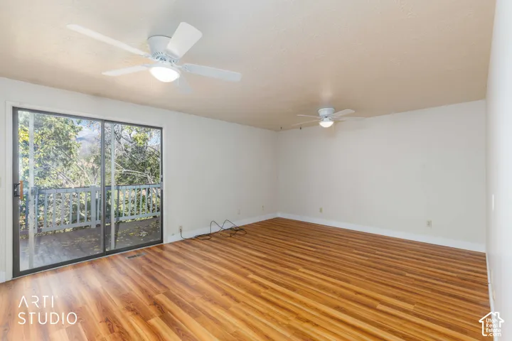 Spacious interior featuring wood-finish flooring, two ceiling fans with integrated lighting, and a large sliding glass door