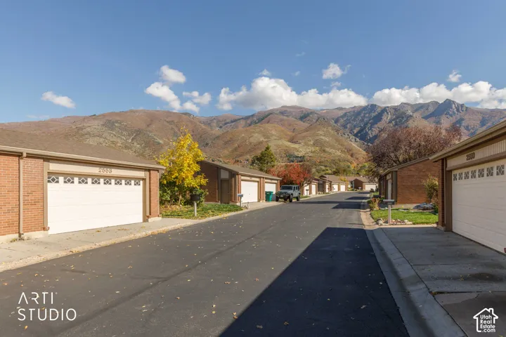 Brick exterior siding, multi-car garage infrastructure, paved surface, and prominent mountain backdrop