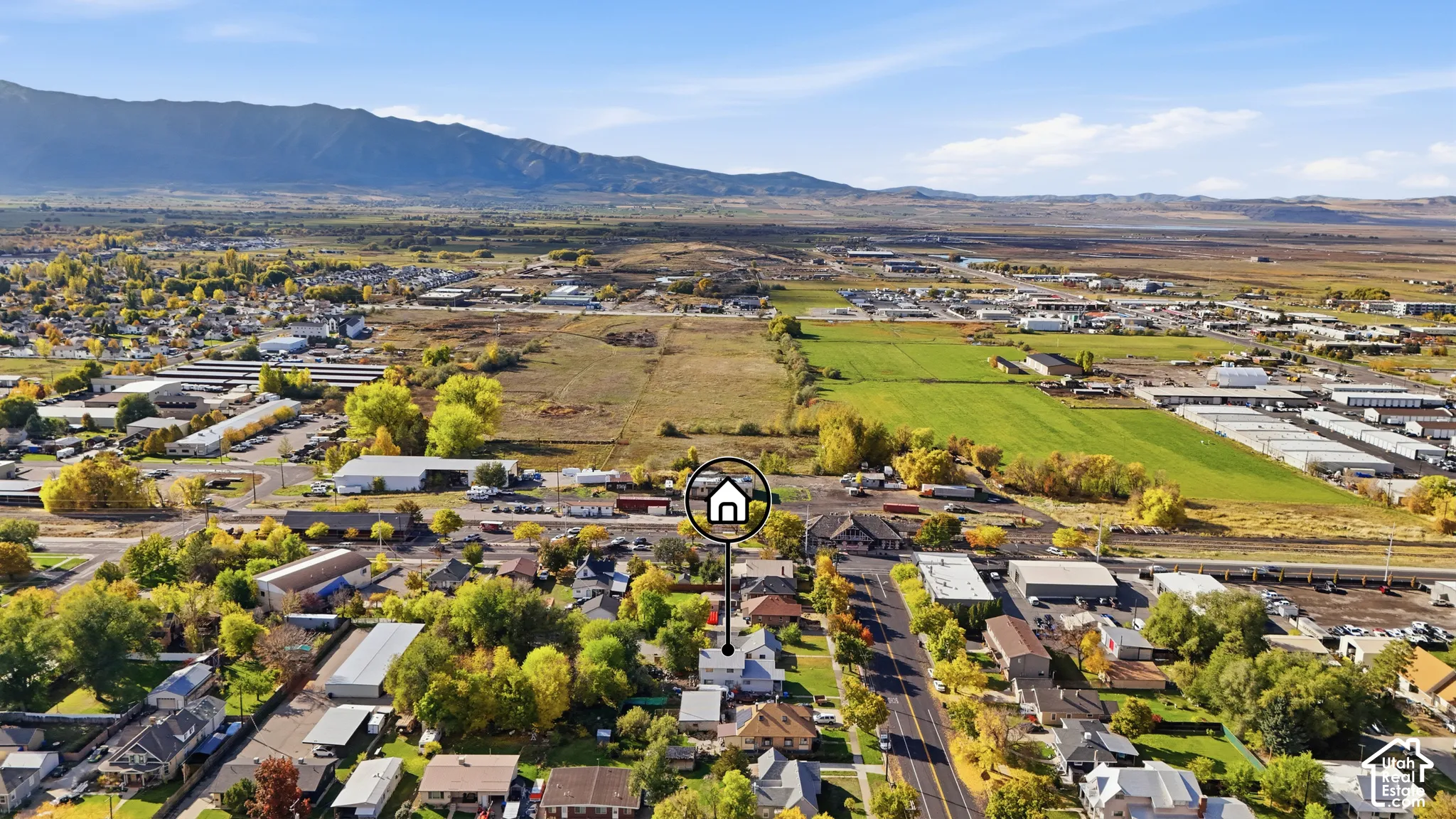 Aerial perspective of residential property featuring a expansive lot, mature trees, and mountainous horizon backdrop