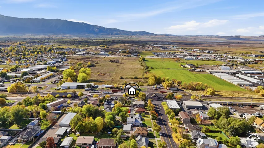Aerial perspective of residential property featuring a expansive lot, mature trees, and mountainous horizon backdrop