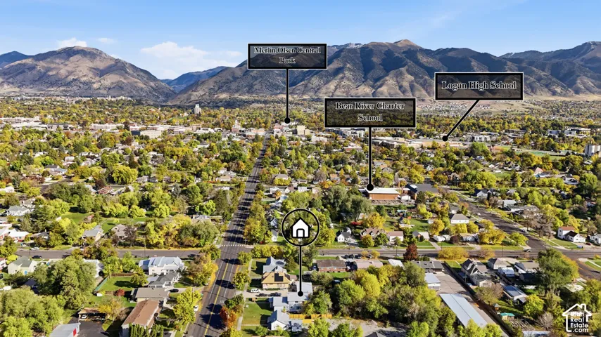 Aerial perspective of the property grounds featuring mature canopy trees, street frontage, and mountain range scenery