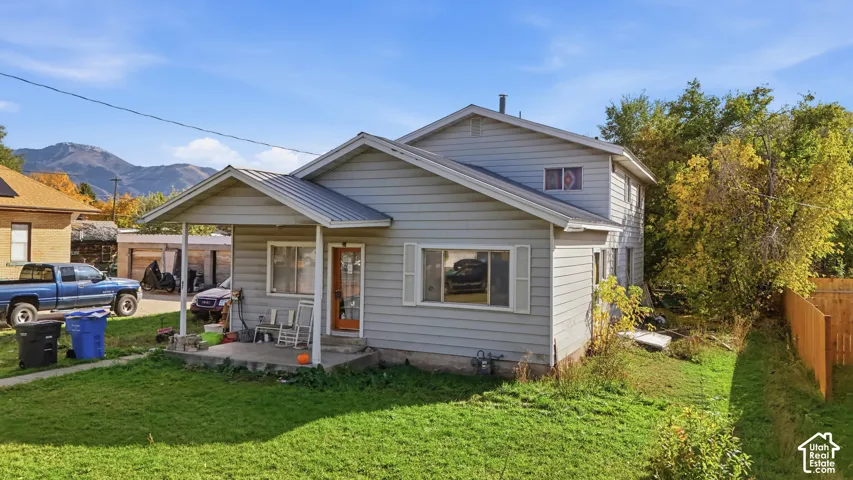 Two-story home with horizontal siding, metal roof, covered front porch, and mountain backdrop