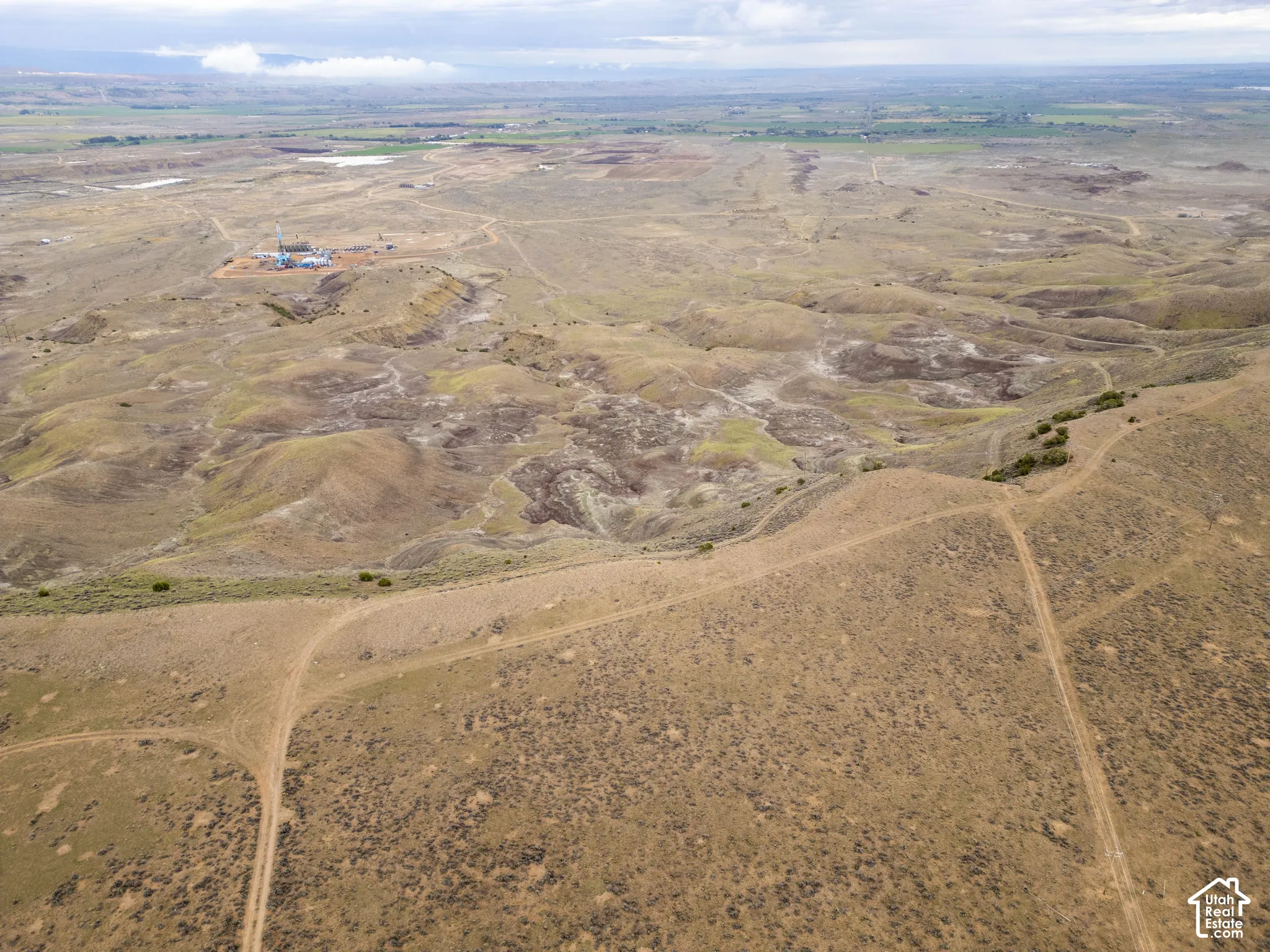 Expansive undeveloped terrain featuring rolling hills, varied topography, and dirt access paths