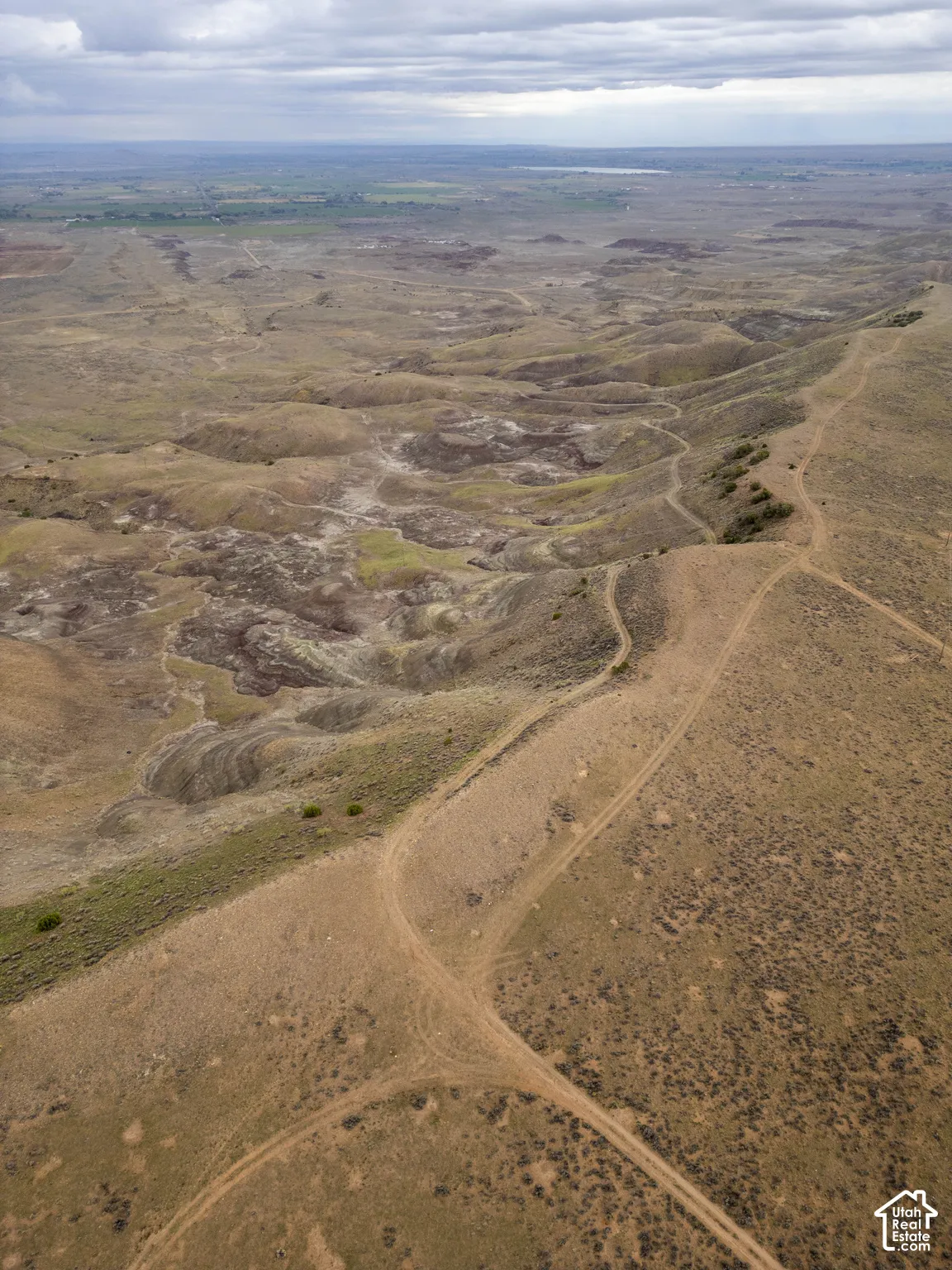 Expansive landscape featuring high-desert topography, undulating terrain, natural rock formations, and earthen trails