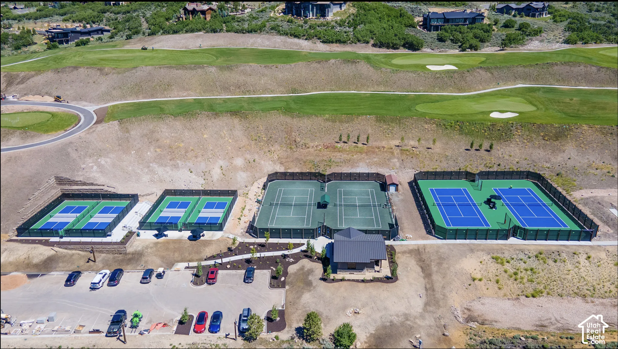 Recreational complex featuring multiple tennis and pickleball courts, a central pavilion, and paved off-street parking