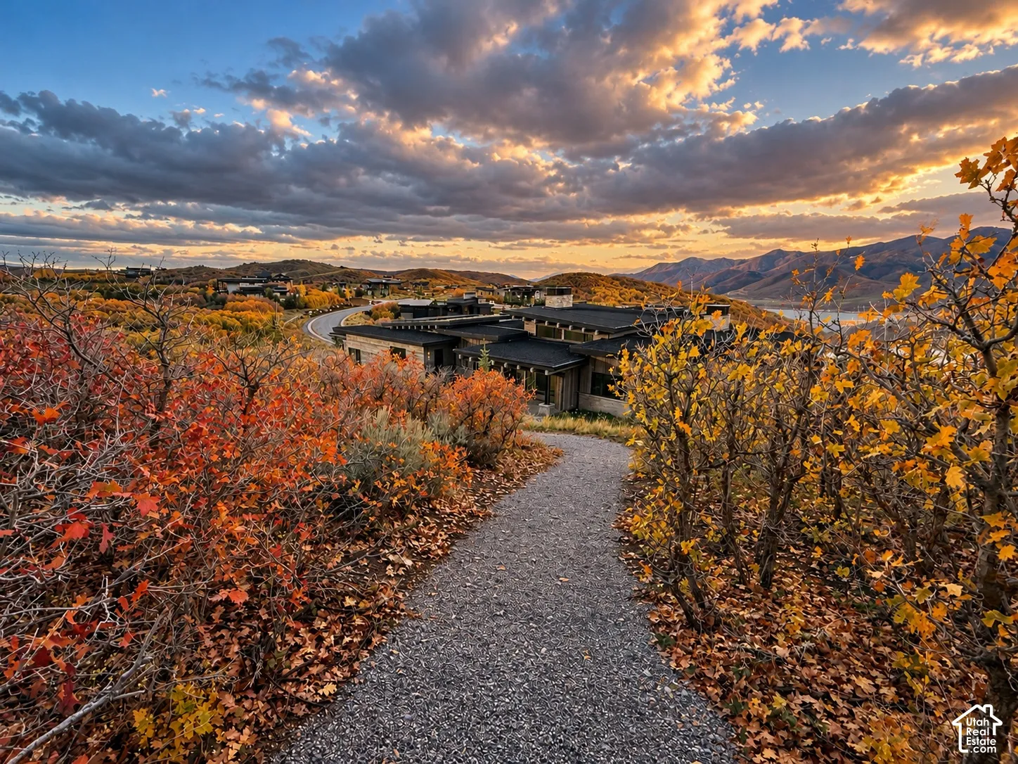 Gravel path leading to a contemporary residence with a low-slope roofline and multi-level structure, set against a mountainous landscape with native foliage