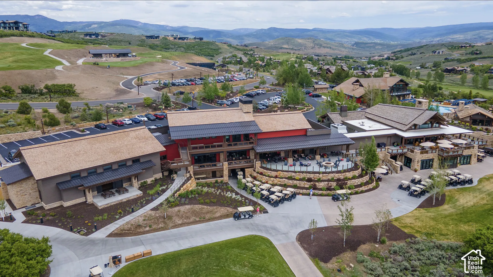 Aerial perspective of multi-building commercial facility featuring stone exterior accents, metal roofing, expansive tiered stone retaining walls, and surrounding mountainous landscape