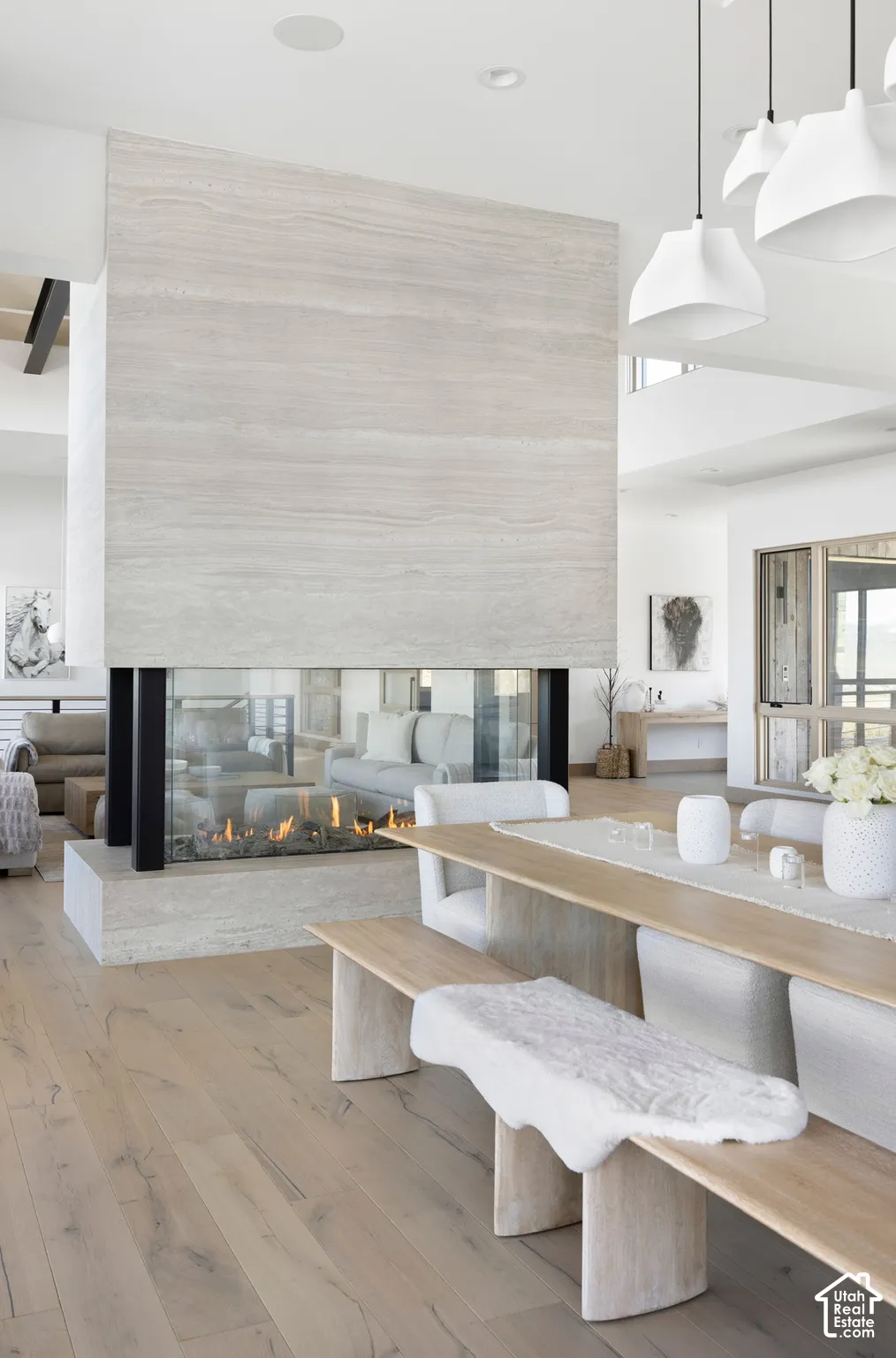 Floor-to-ceiling stone-clad double-sided fireplace, wood-finish flooring, and recessed ceiling lighting