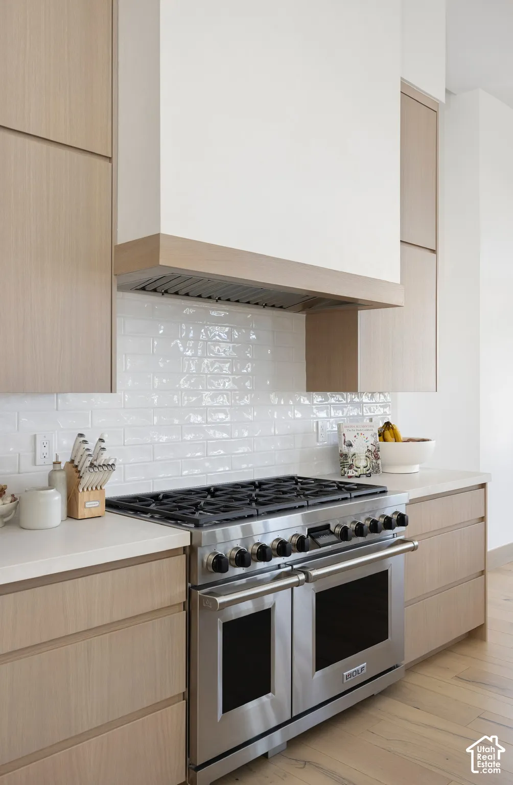 Custom wood-finish cabinetry, professional-grade stainless steel range, light-toned countertop, and white subway tile backsplash