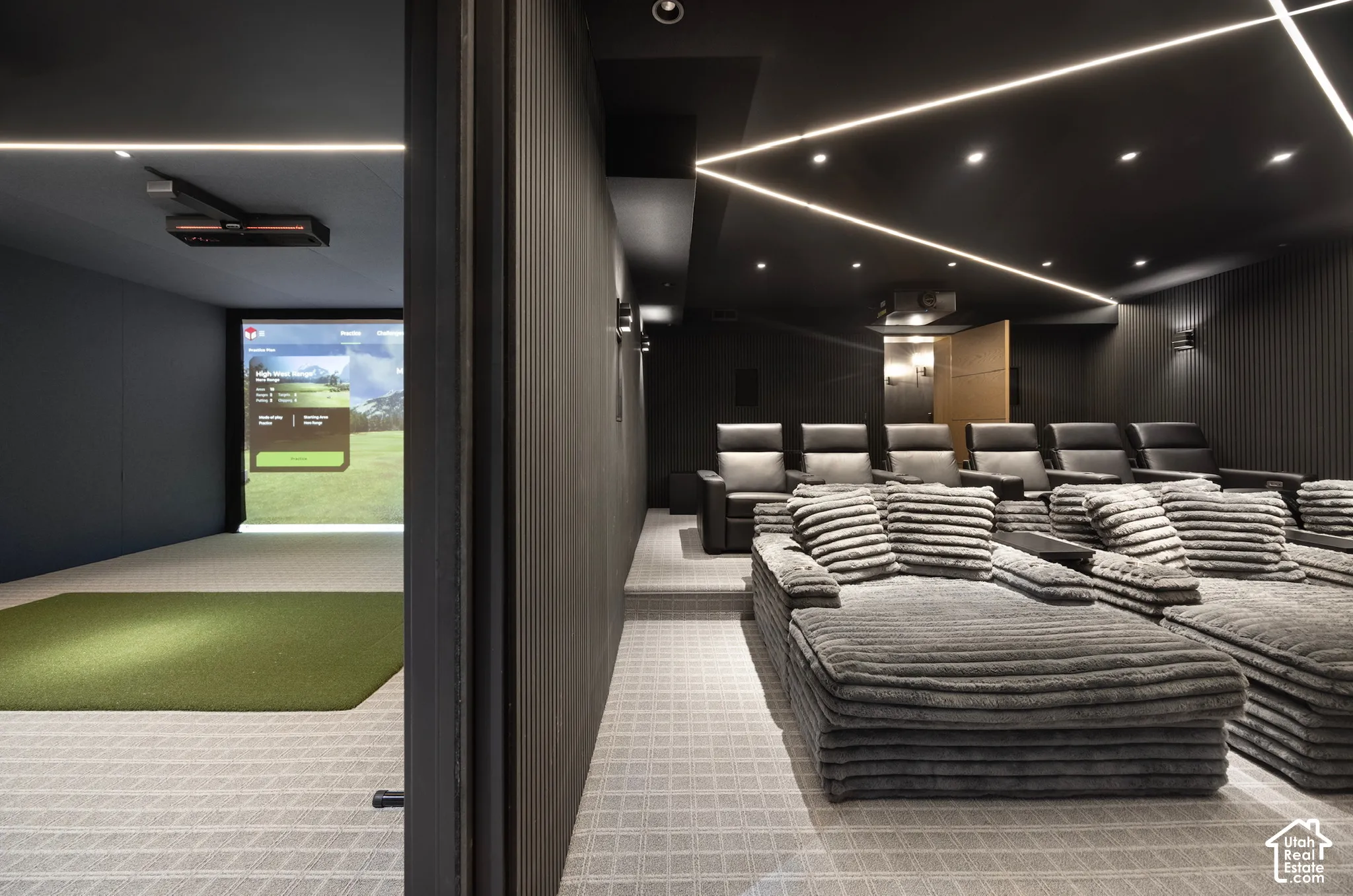 Dedicated simulator room featuring a synthetic turf hitting mat and projection screen, complemented by a tiered media room with linear LED ceiling lighting and textured wall paneling