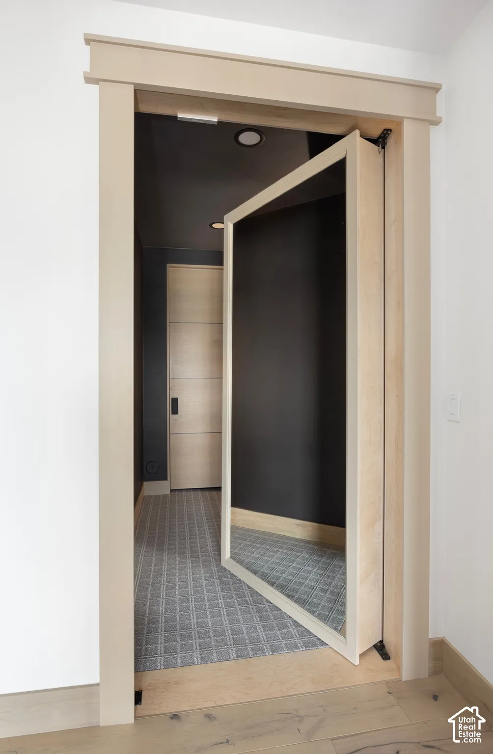 Pivot door with light wood-finish trim, integrated mirror panel, recessed ceiling lighting, and patterned wall-to-wall carpeting