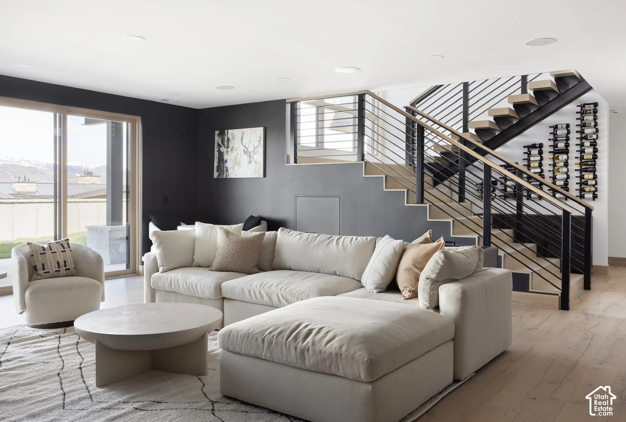 Open floor plan featuring wood-finish flooring, a modern staircase with cable railings and wood treads, built-in wine storage, and large sliding glass doors