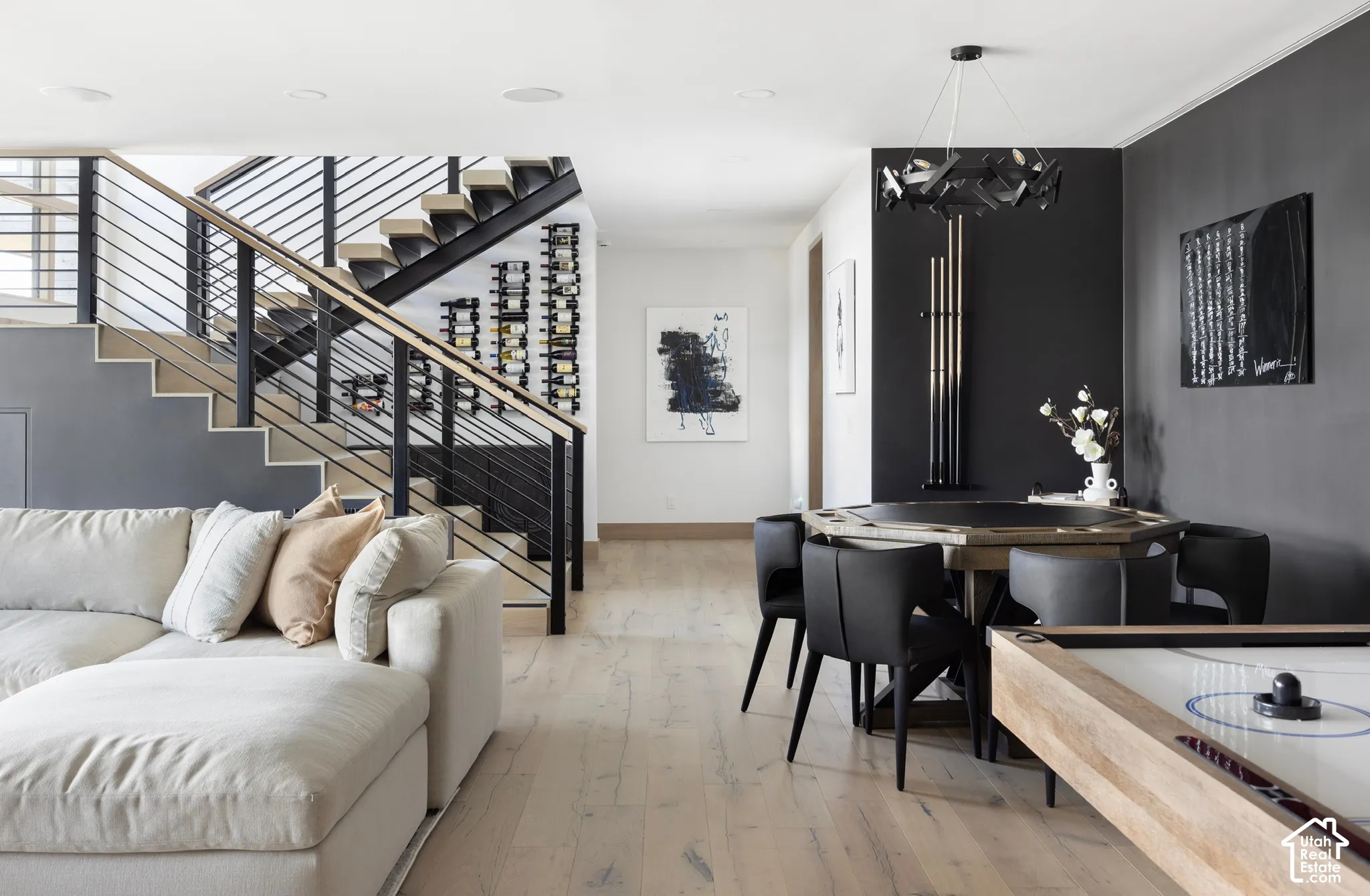 Open-riser staircase featuring metal railings, wood-finish flooring, built-in wine storage, and a modern sculptural chandelier