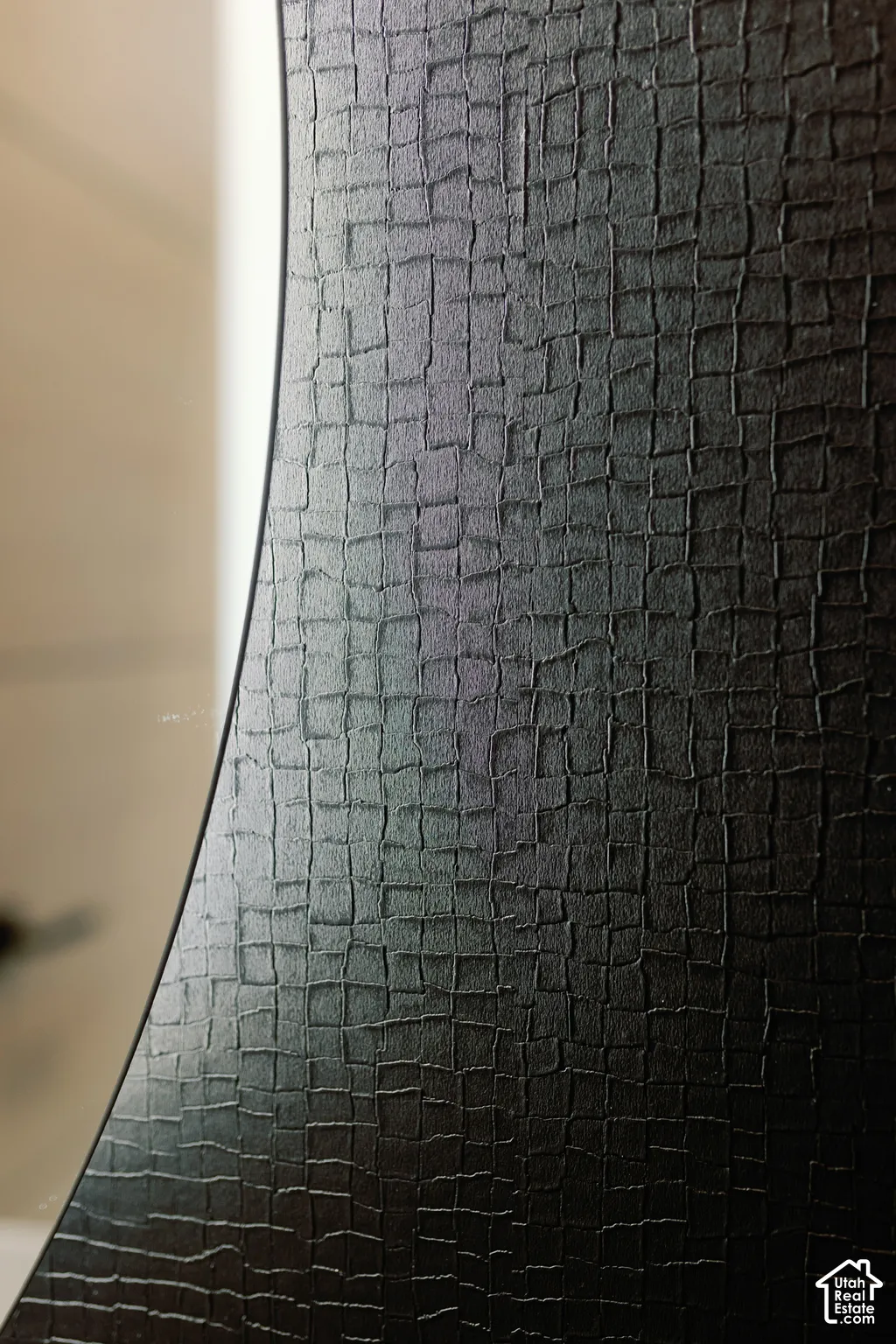 Black textured cabinet door featuring a subtle grid pattern and curved profile edge
