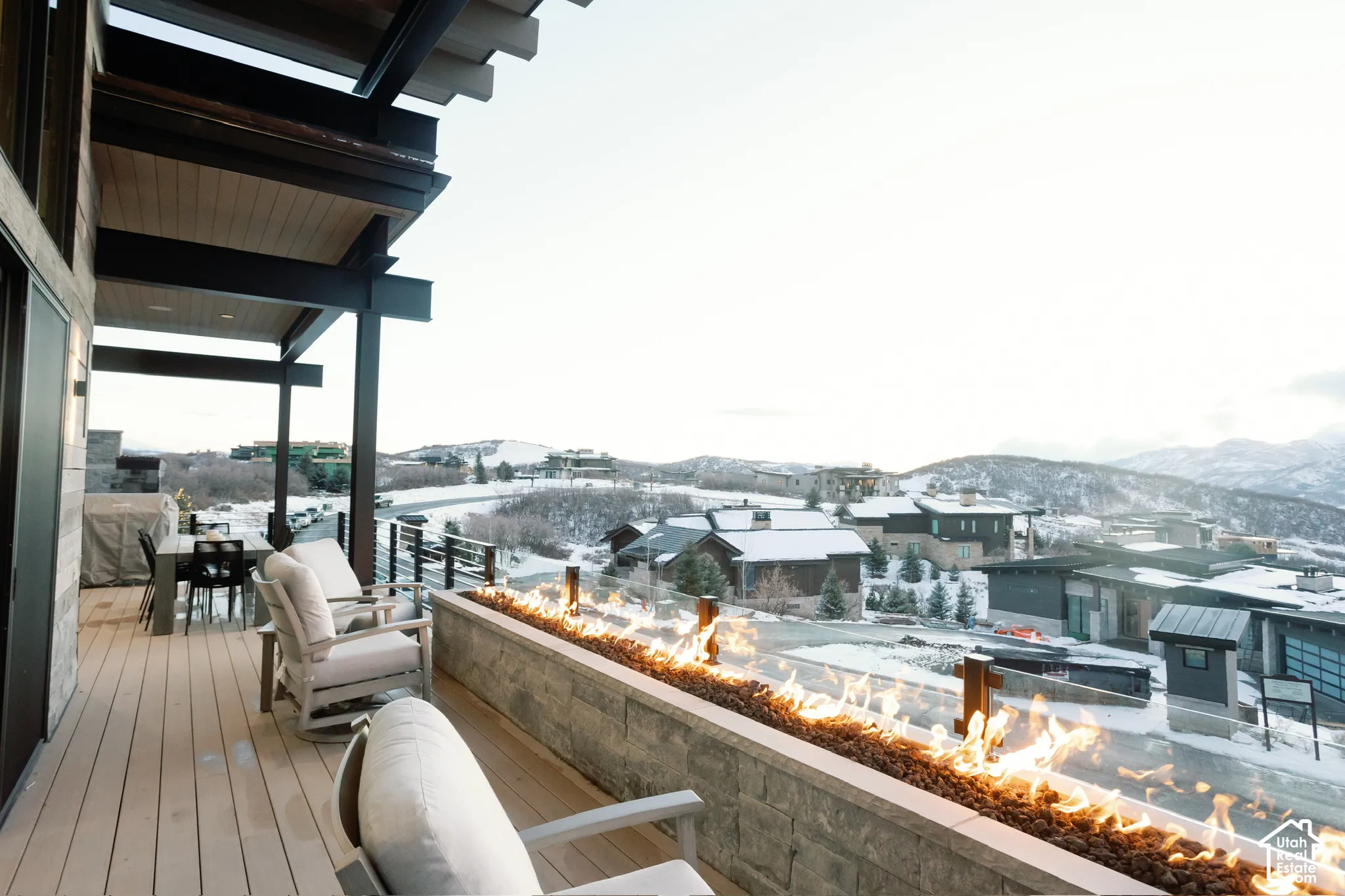 Covered deck featuring composite decking, linear built-in gas fire feature with stone masonry surround, and metal cable railing