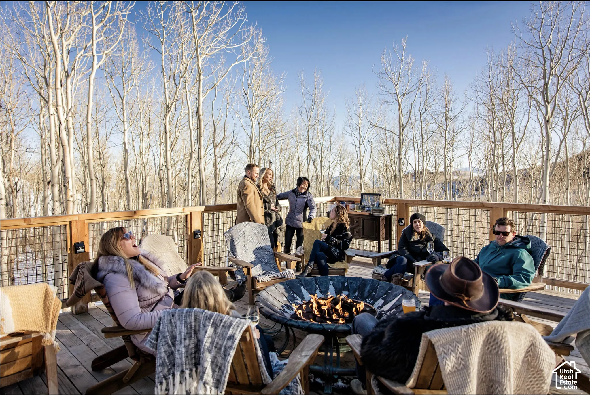 Expansive elevated wood deck featuring integrated wire mesh railings and surrounding mature aspen forest