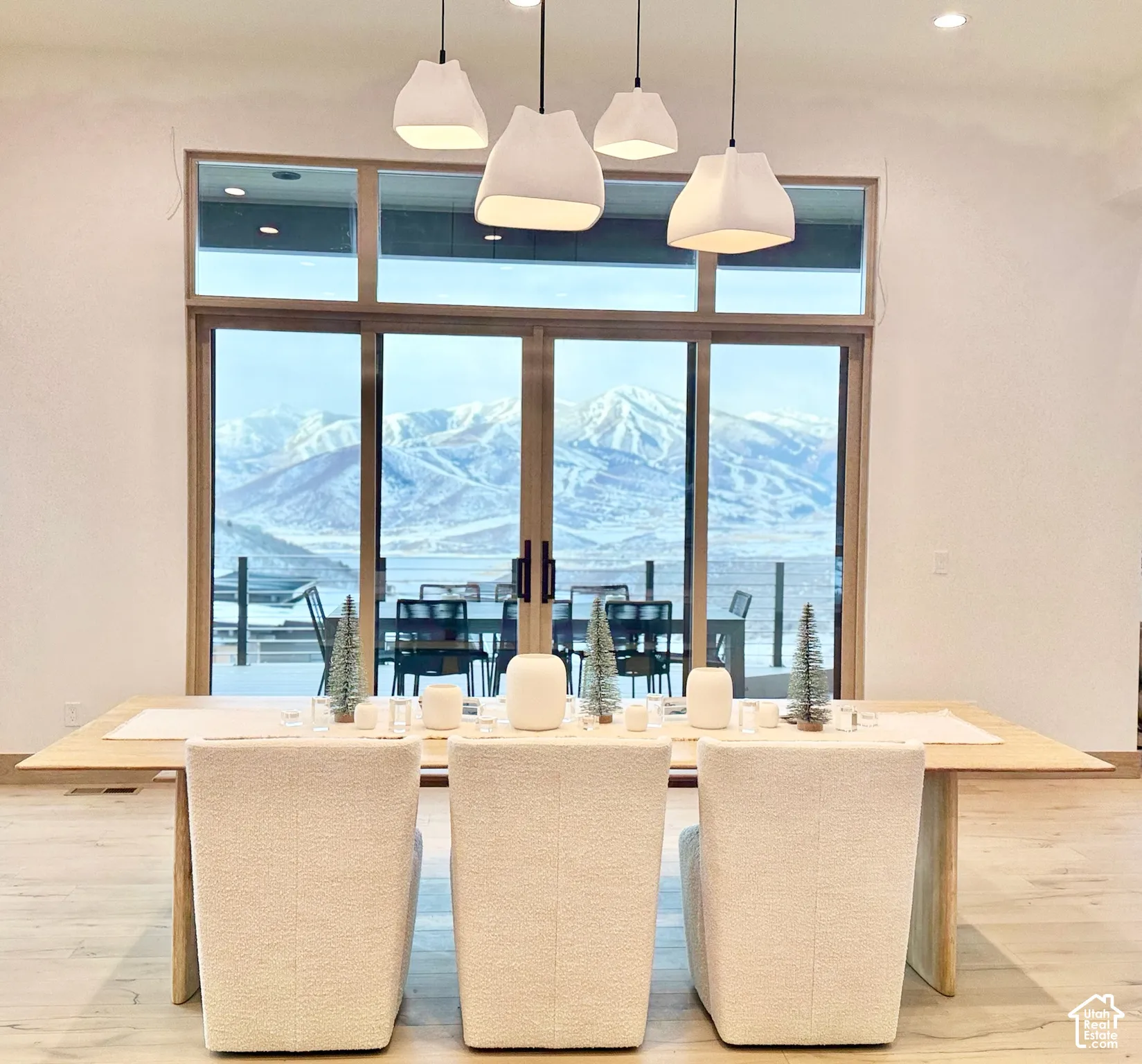 Floor-to-ceiling multi-panel sliding glass doors with transom windows, four pendant light fixtures, and wood-finish flooring