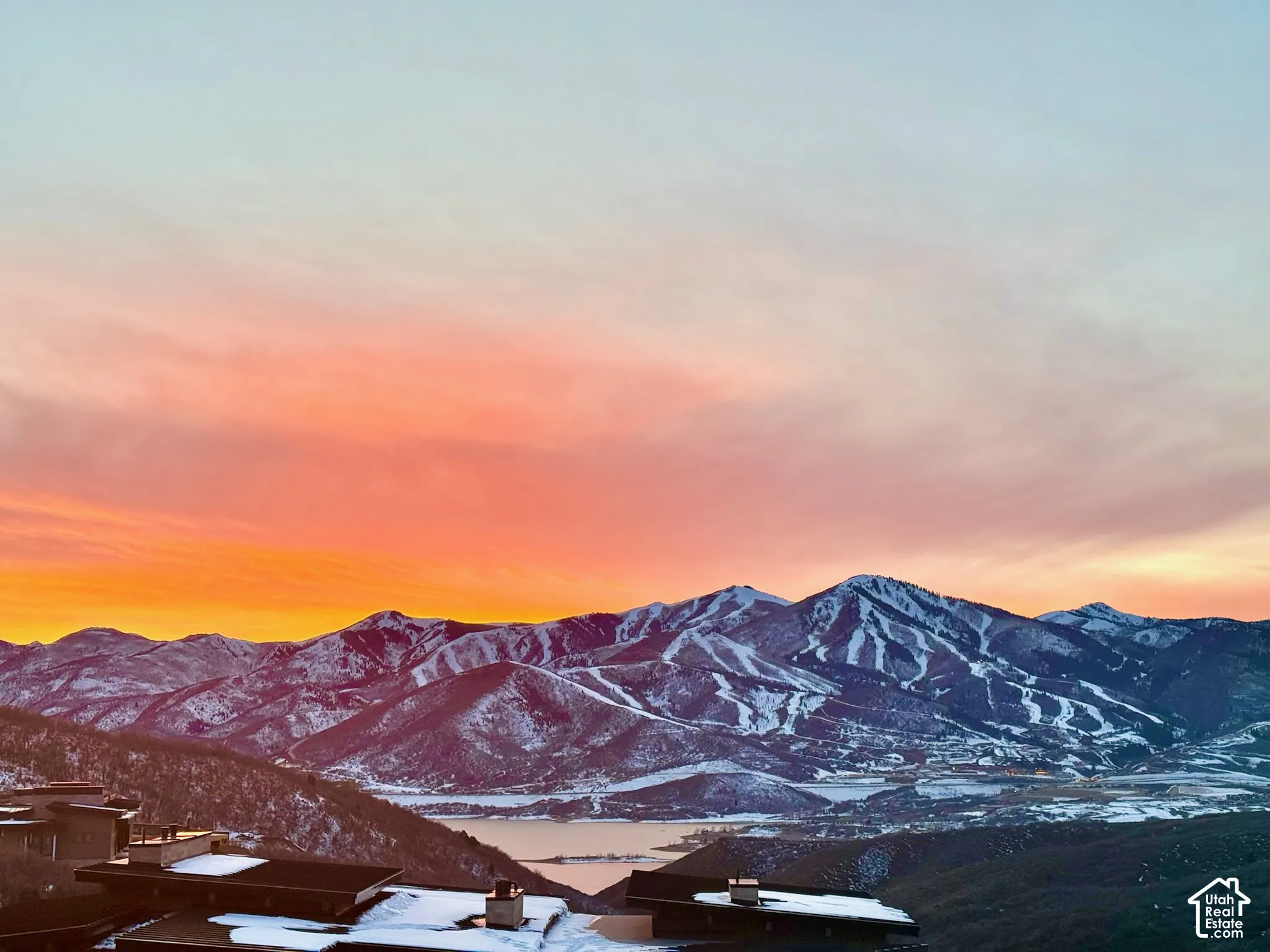 Elevated mountainous topography with snow-capped peaks and expansive water frontage under a twilight sky