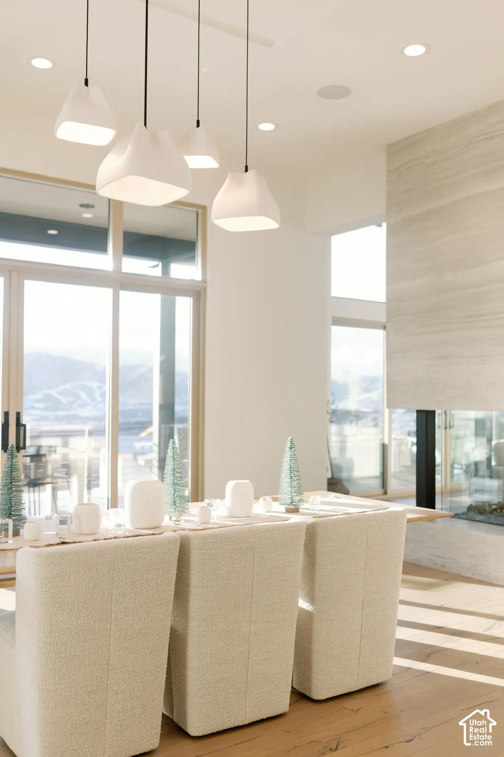 Modern pendant lighting, floor-to-ceiling glass sliding doors, wood-finish flooring, and a full-height stone-clad fireplace