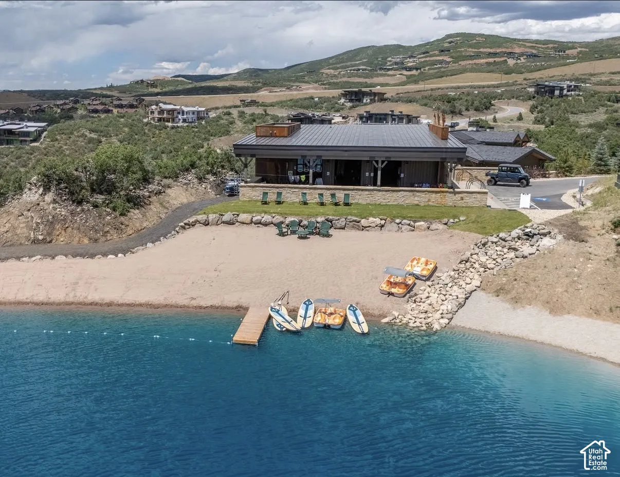 Waterfront property featuring a private sandy beach, tiered stone retaining walls, metal roof structure, and a wood-plank dock