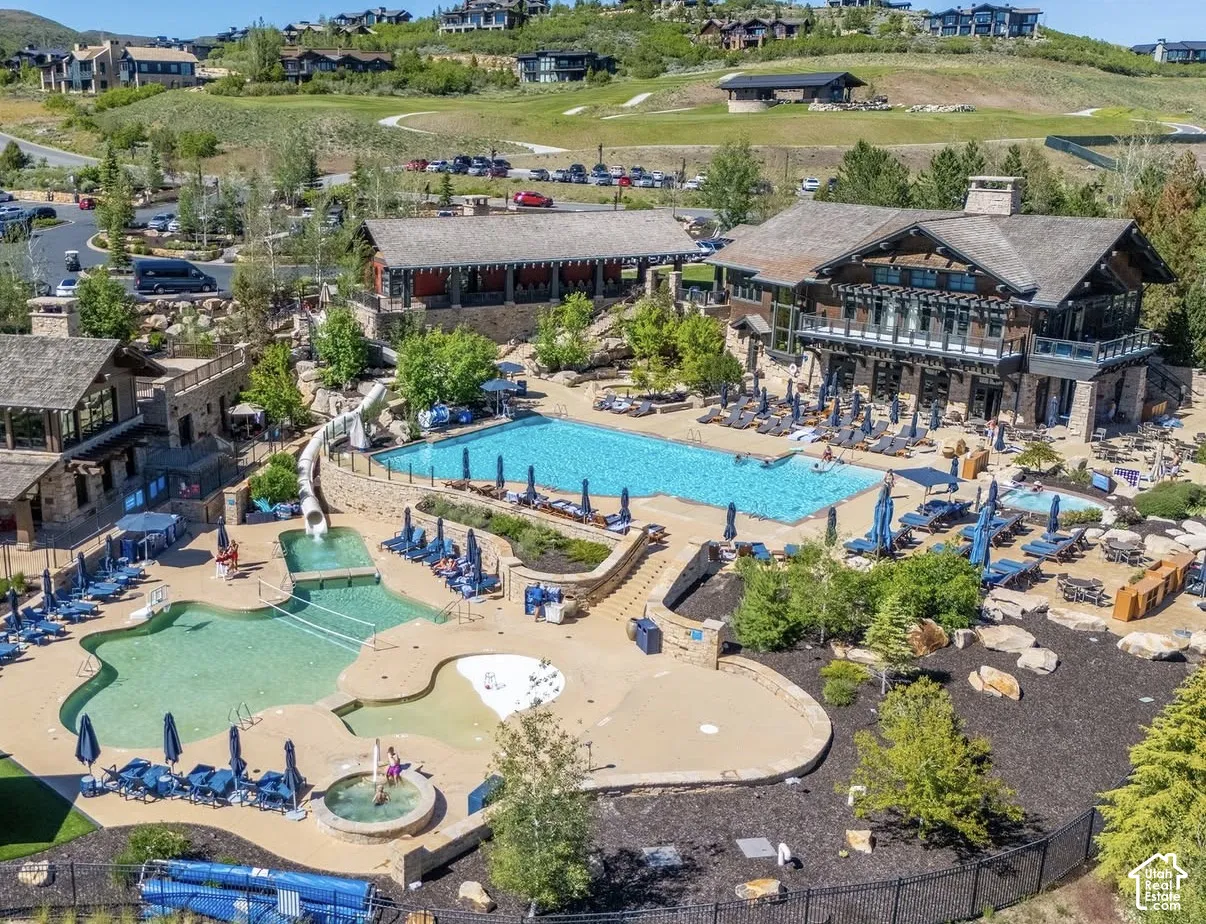 Multi-level clubhouse with stone exterior, expansive swimming pool, integrated water slide, shallow wading area, and hot tub
