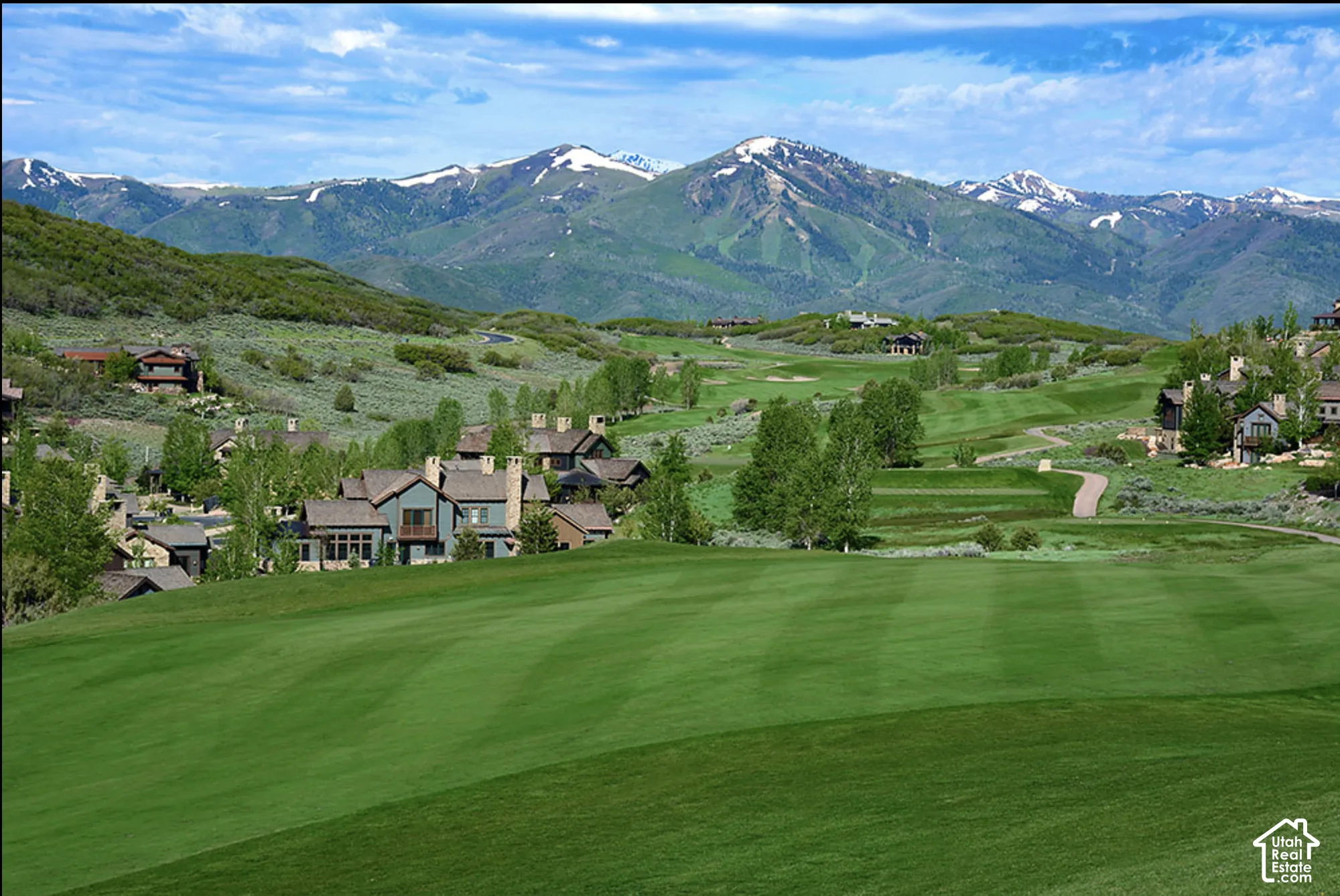 Expansive manicured lawn, golf course terrain, and snow-capped mountain backdrop