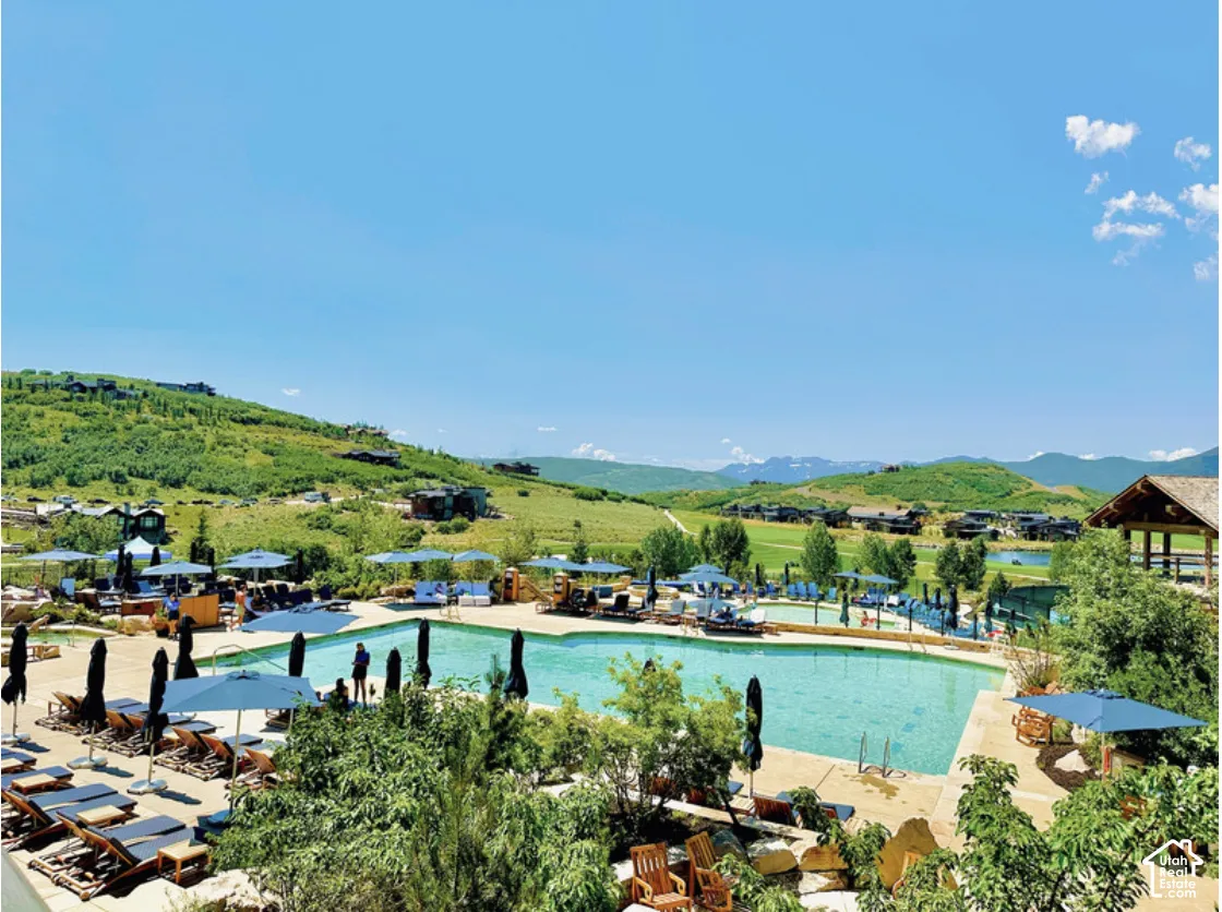 Outdoor swimming pool with stone decking, surrounding mountain landscape, and integrated pavilion structure