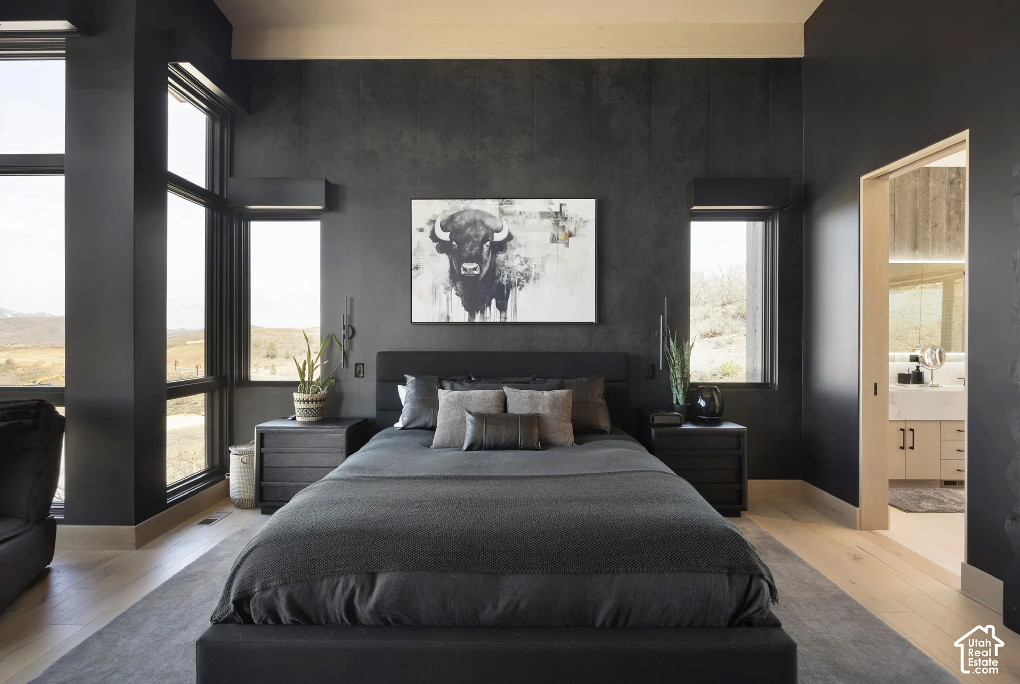 Floor-to-ceiling windows, matte charcoal feature wall, light wood-finish flooring, and minimalist window casings