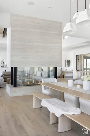 Floor-to-ceiling stone-clad double-sided fireplace, wood-finish flooring, and recessed ceiling lighting