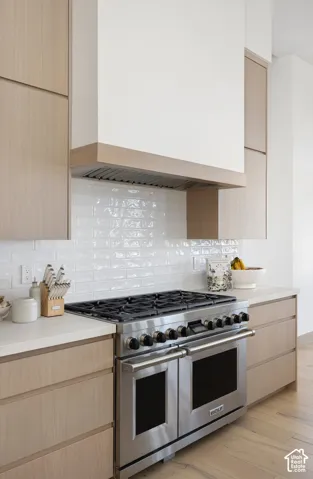 Custom wood-finish cabinetry, professional-grade stainless steel range, light-toned countertop, and white subway tile backsplash
