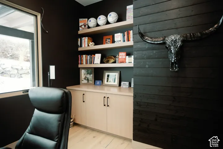 Custom built-in light-tone cabinetry, horizontal black wood-plank accent wall, and three open floating shelves featuring wood-finish surfaces and large window