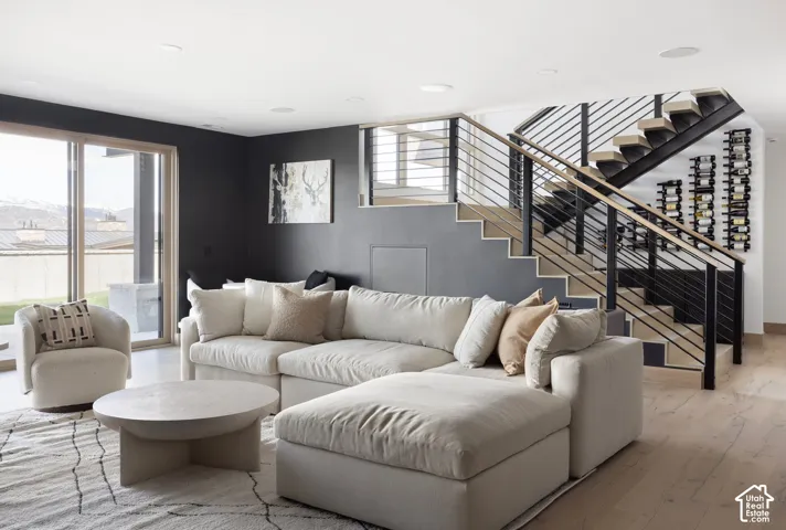 Open floor plan featuring wood-finish flooring, a modern staircase with cable railings and wood treads, built-in wine storage, and large sliding glass doors