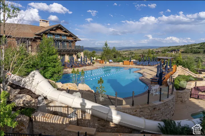 Swimming pool with lap lanes and integrated water slide, stone retaining walls, and mountain scenery